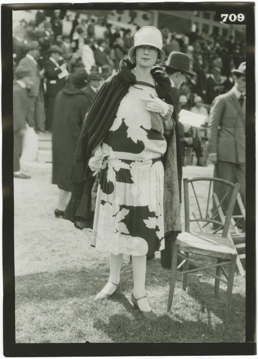 Frau in Kleid und Mantel auf dem Rennplatz in Deauville