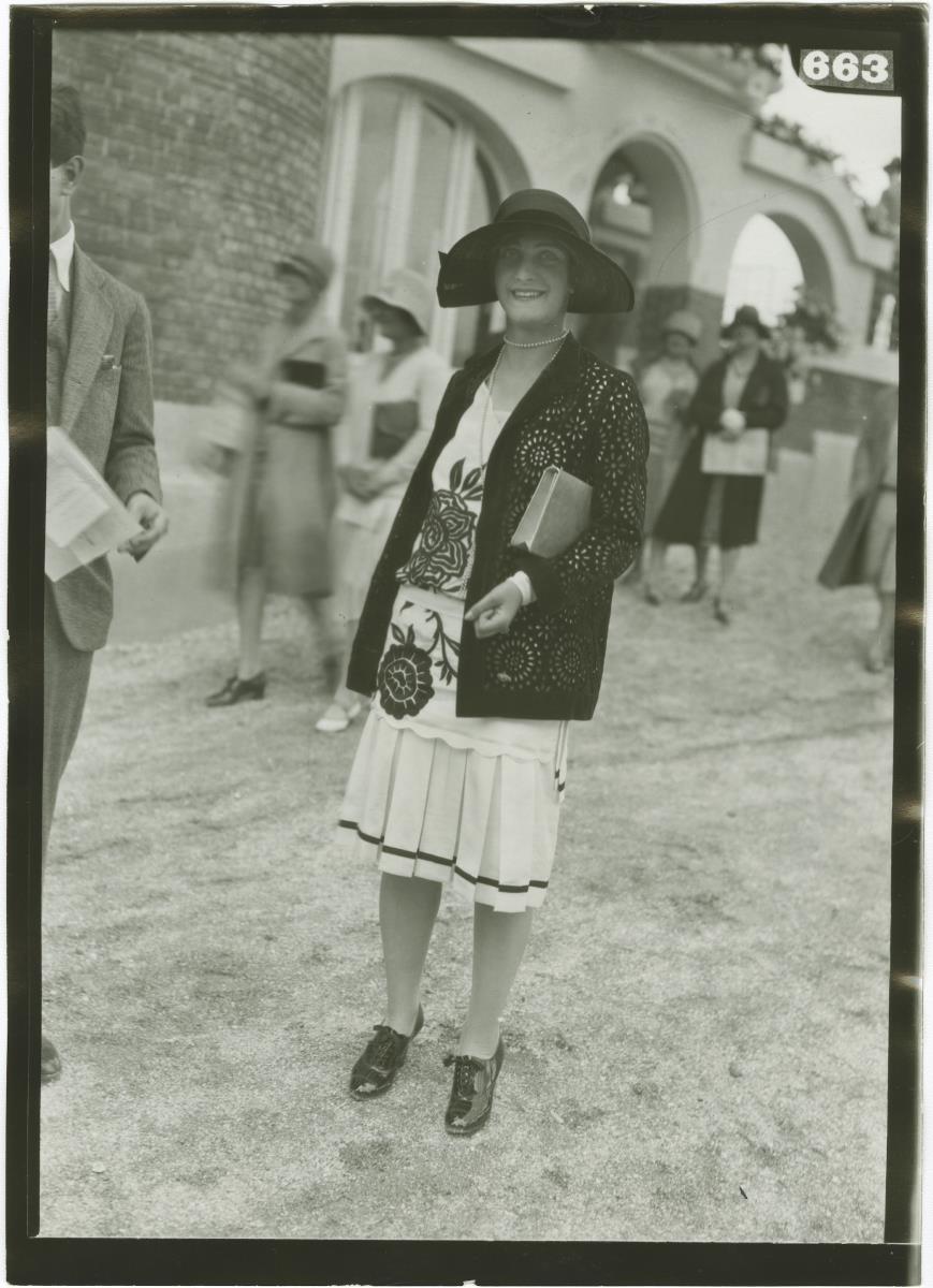 Frau in Kleid und Jacke auf dem Rennplatz in Deauville
