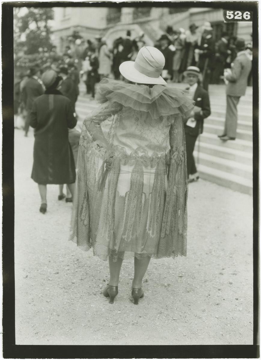 Frau in Kleid und Mantel auf dem Rennplatz in Auteuil