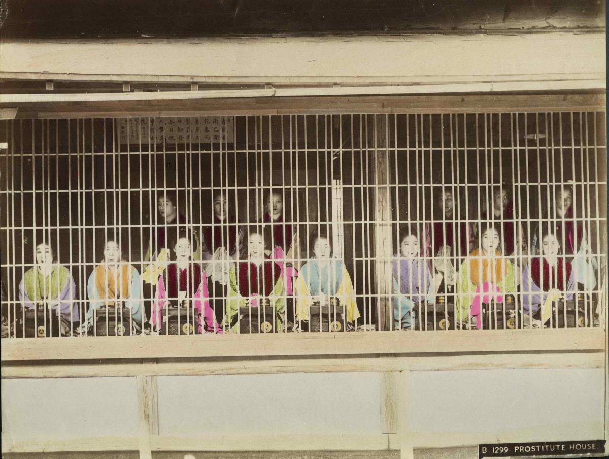 Junge Frauen in einem Hause, hinter  einem Gitter sitzend