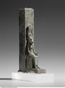 Tiersarg in Form eines Obelisken, davor eine Figur der thronenden Göttin Wadjet