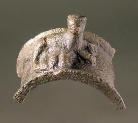 "Hälfte eines breiten Rings, darauf eine gelagerte säugende Hündin" (tatsächlich Teil eines ägyptischen Sistrums mit säugender Katze)