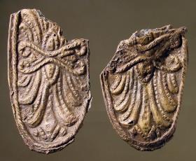 Zwei Bruchstücke ovaler mit erhabener Verzierung versehener Belagstücke aus mit Bronze hinterlegtem Silberblech