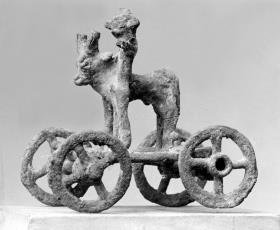 Primitive Statuettengruppe eines stehenden, nackten Mannes mit Stier auf einem vierrädrigen Wagen