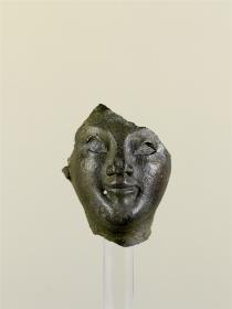 Fragment eines Kopfes, Gesicht, Teile vom Hals, Stirn und rechtem Ohr, Loch unterhalb des rechten Mundwinkels, Nase eingedrückt, Hohlguss, Augen waren eingelegt